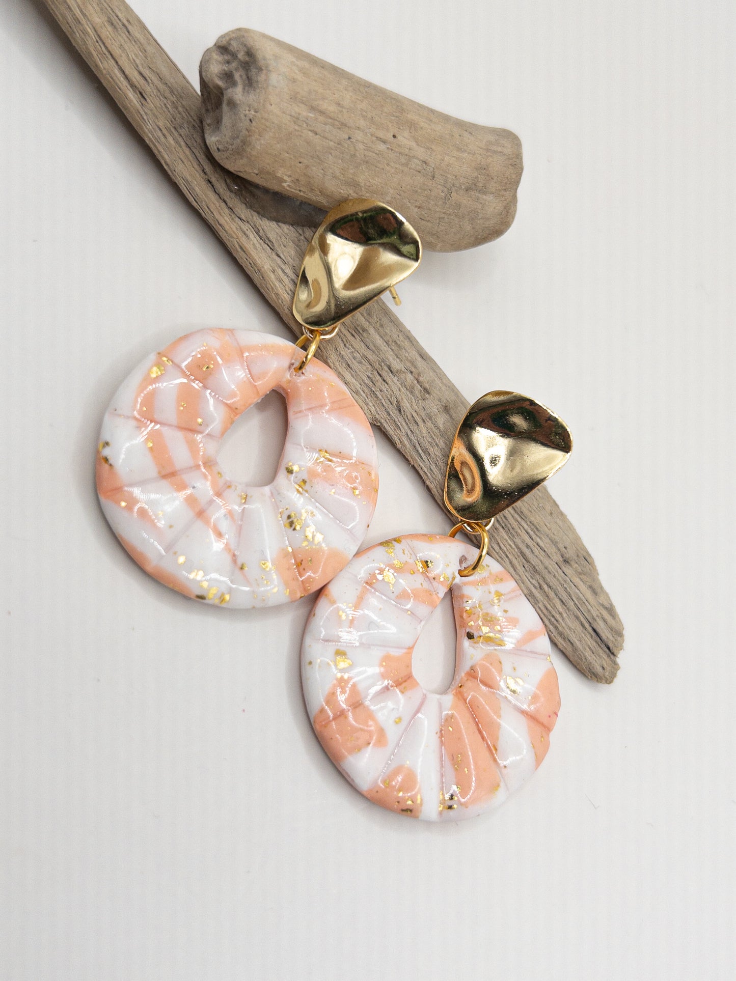 Oorbellen goudkleurige oorstekers in driehoek met ronde hanger in wit perzikkleur en goud met glans