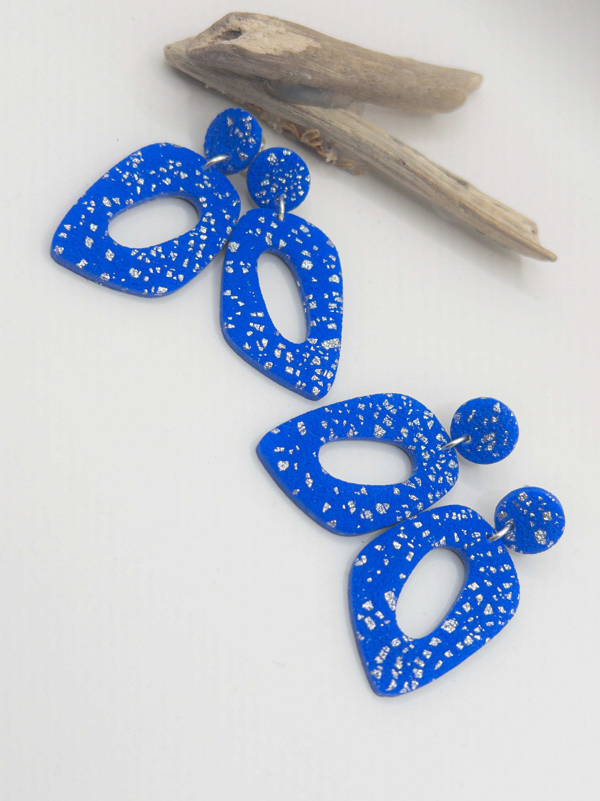 Oorbellen in speelse vorm blauw met kleine zilveren spatjes. Oorstekers met achterkantjes.